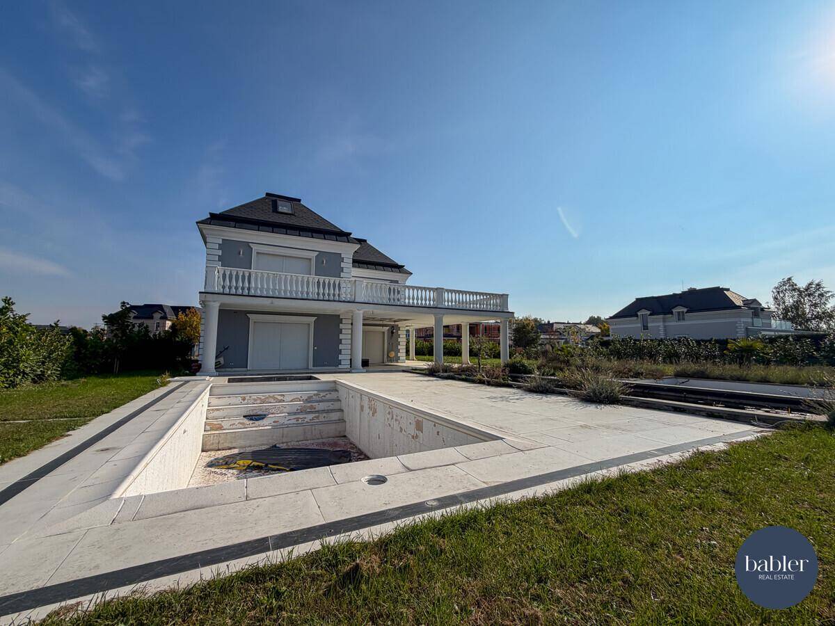 Außenansicht der Villa mit im Bau befindlichem Poolbereich und weitläufigem Garten.