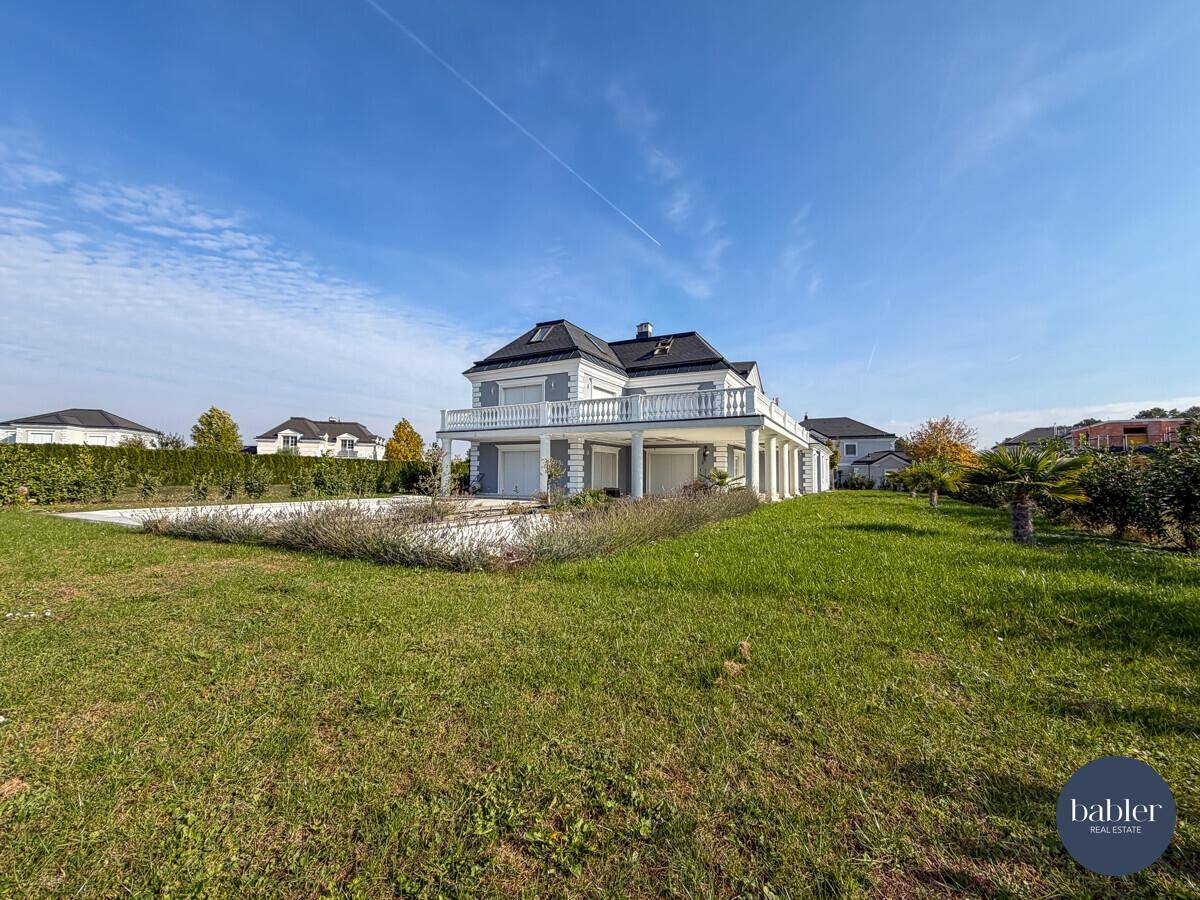 Weitläufiger Gartenbereich der Villa mit Rasenfläche und Blick auf das Gebäude.
