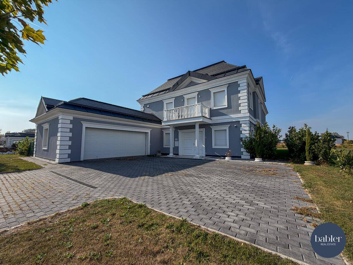 Elegante Villa mit Doppelgarage, gepflasterter Auffahrt und klassischer Architektur.