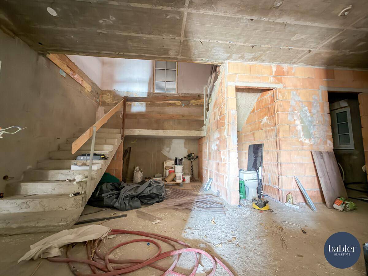 Treppenbereich im Rohbau mit unfertiger Treppe und sichtbaren Bauelementen.