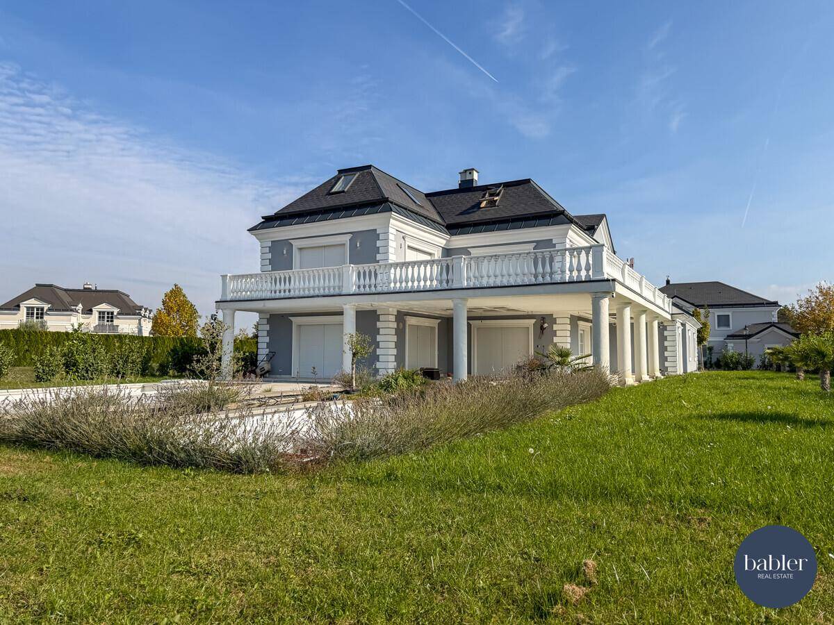 Seitliche Ansicht der Villa mit weitläufigem Garten und vorbereitetem Poolbereich.