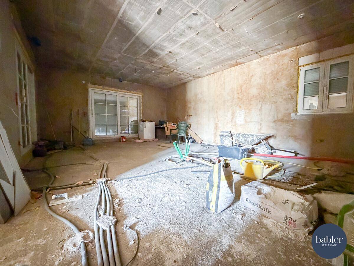 Rohbauzimmer mit Baumaterialien, Schiebetür und Fenster, bereit für den Ausbau.