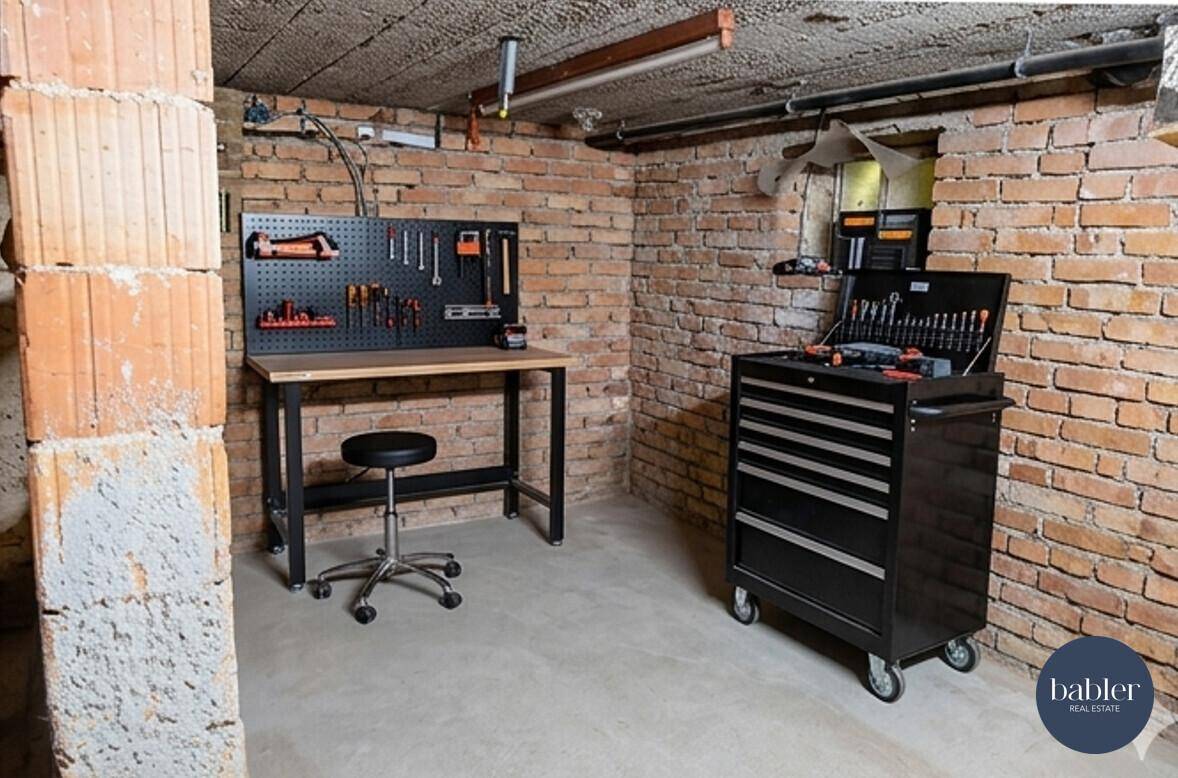 Werkstatt im Keller mit Ziegelwänden, Werkbank und Werkzeugschrank.