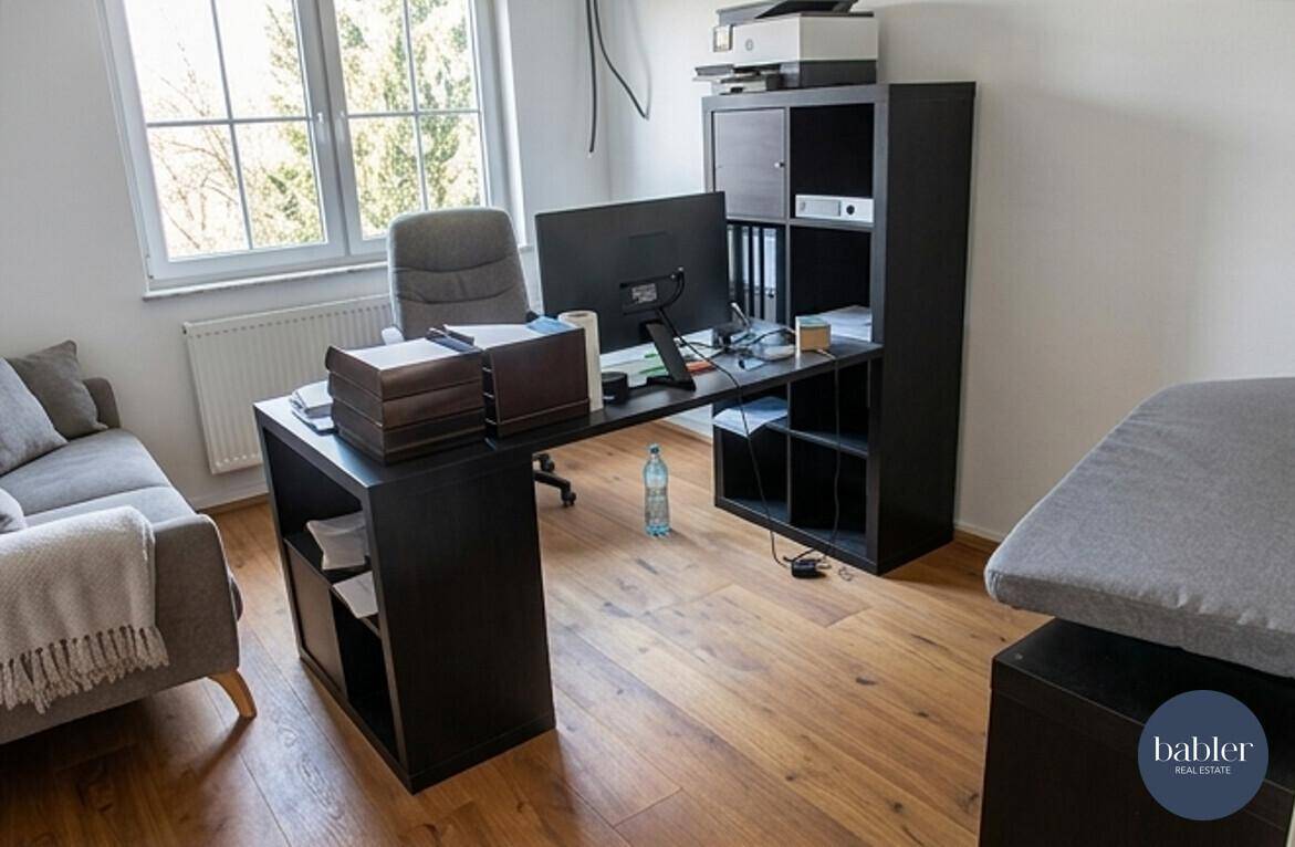 Geräumiges Heimbüro mit großem Schreibtisch, Sofa und Blick ins Grüne.