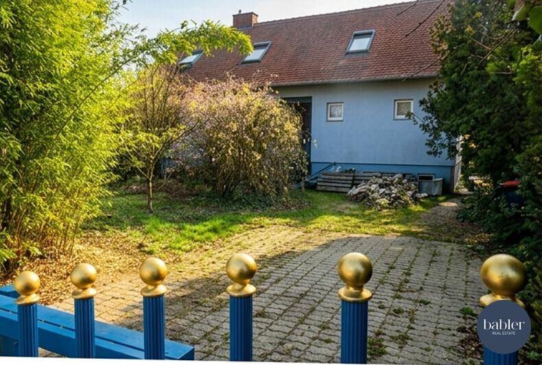 Rückseite des Hauses mit gepflasterter Auffahrt und Gartenbereich.