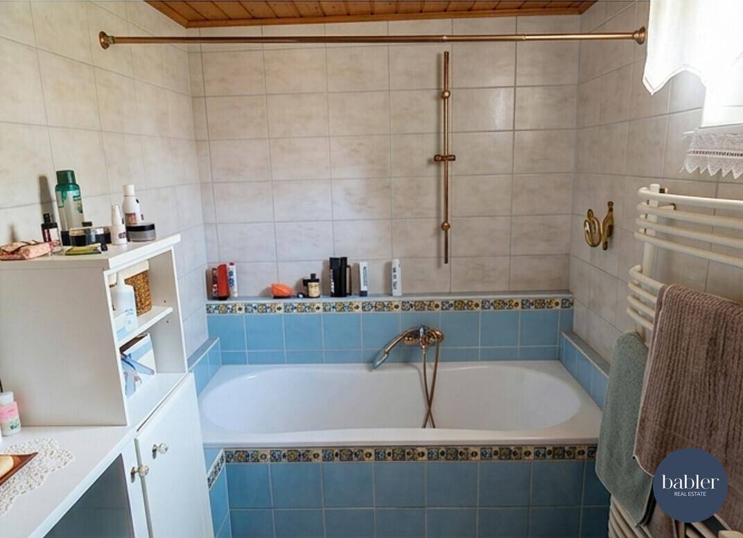 Badezimmer mit blauen und weißen Fliesen, Badewanne und beheiztem Handtuchhalter.