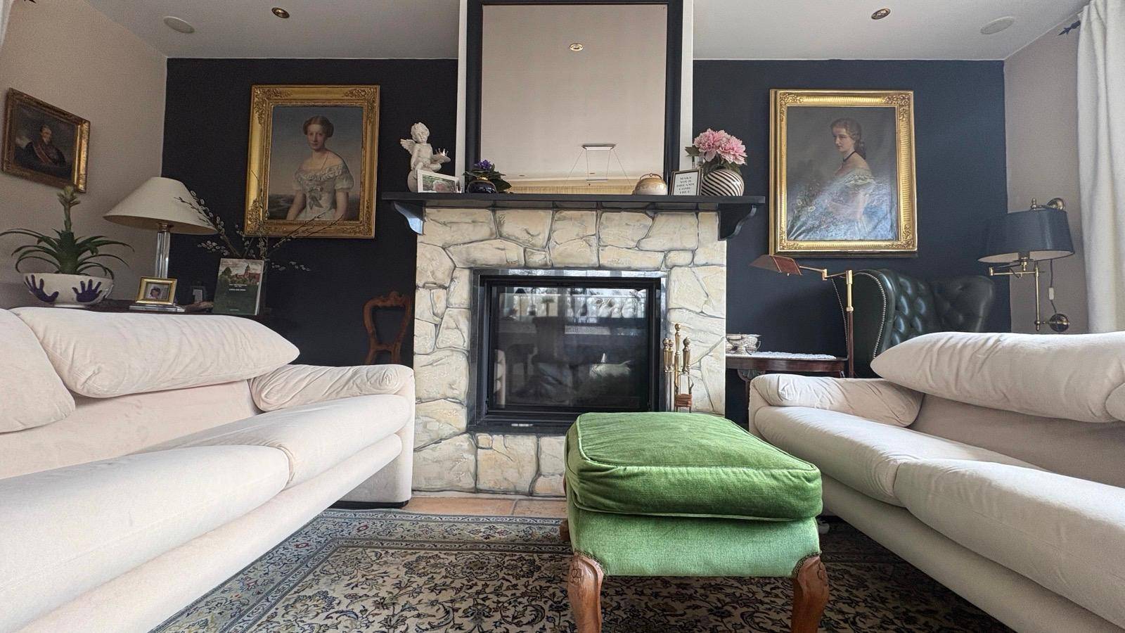 Gemütliches Wohnzimmer mit Steinkamin, bequemen Sofas und klassischer Dekoration.