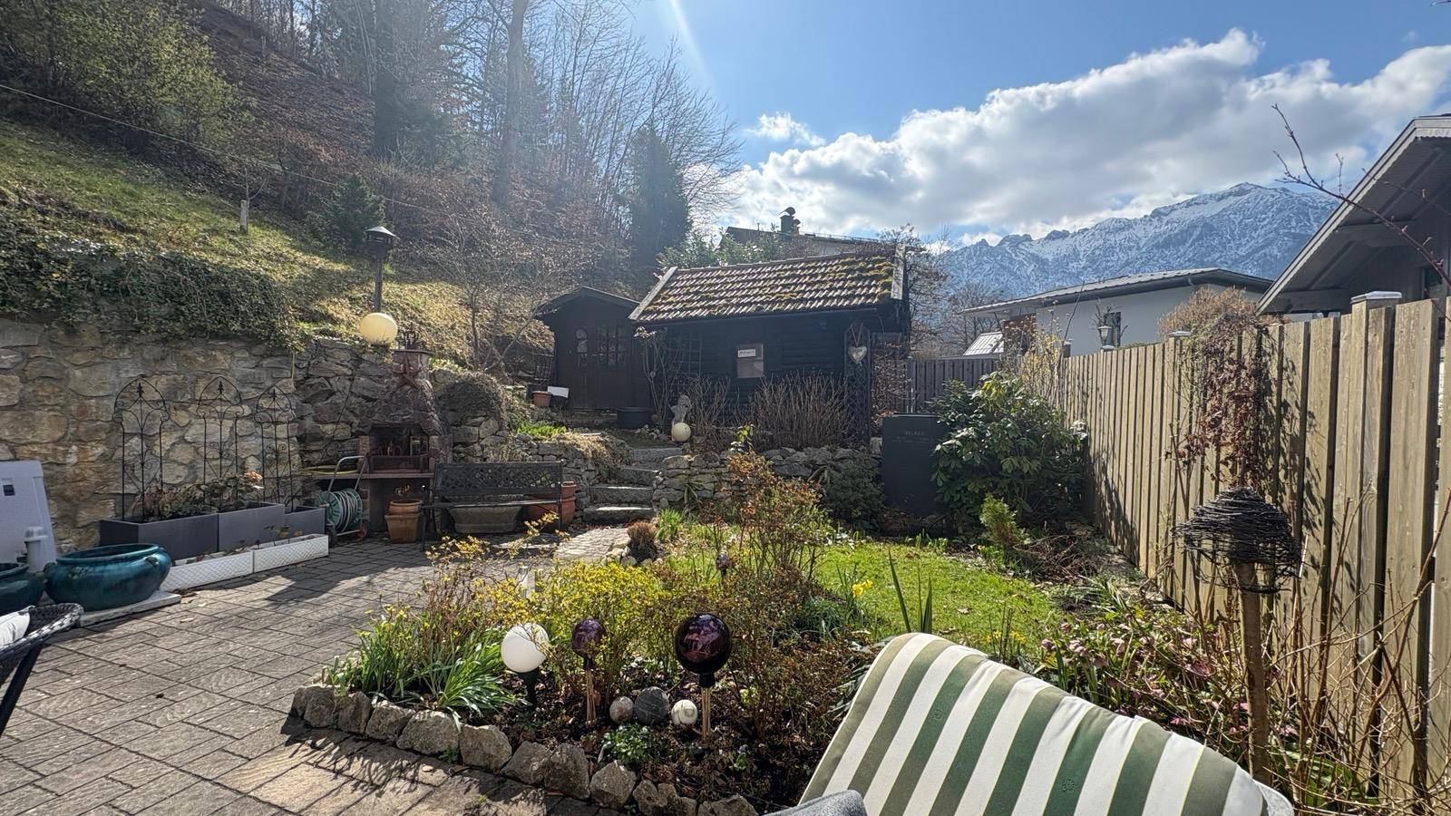 Gepflegter Garten mit Bergblick, Grillplatz und kleinem Gartenhaus.