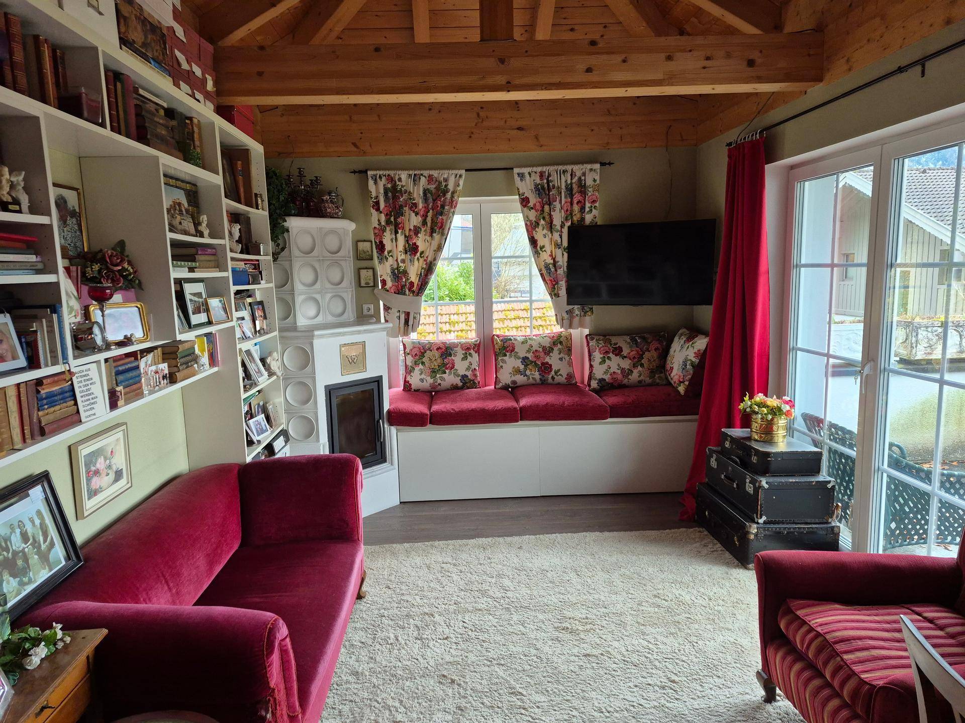 Rustikales Wohnzimmer mit Holzbalkendecke, Kachelofen und gemütlicher Sitzecke.