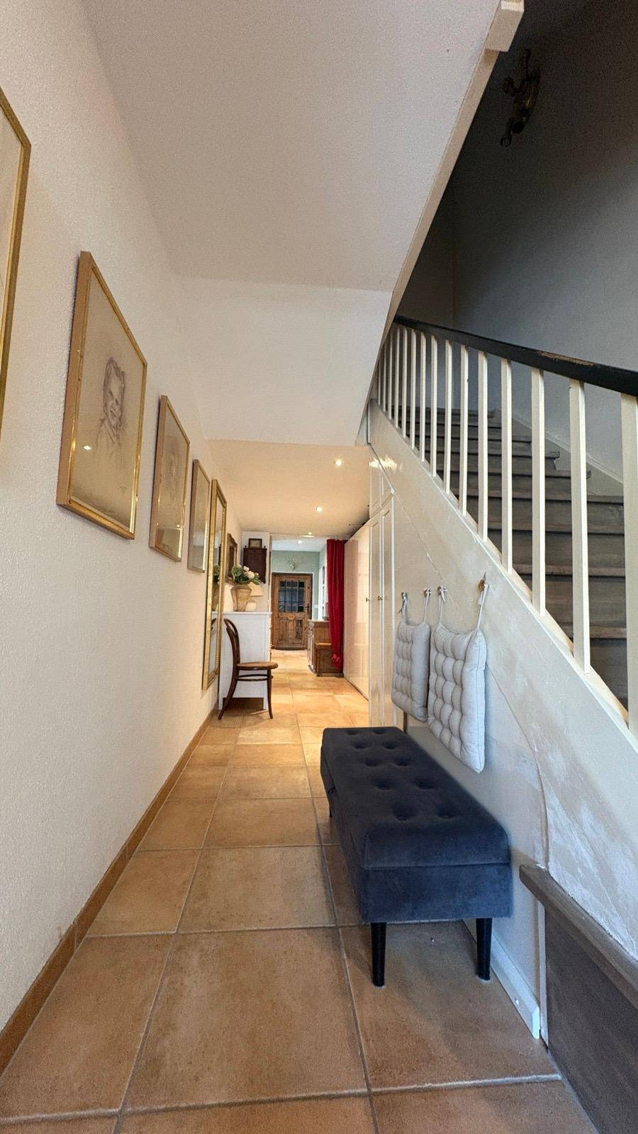 Geräumiger Flur mit Treppe, Sitzbank und Fliesenboden.