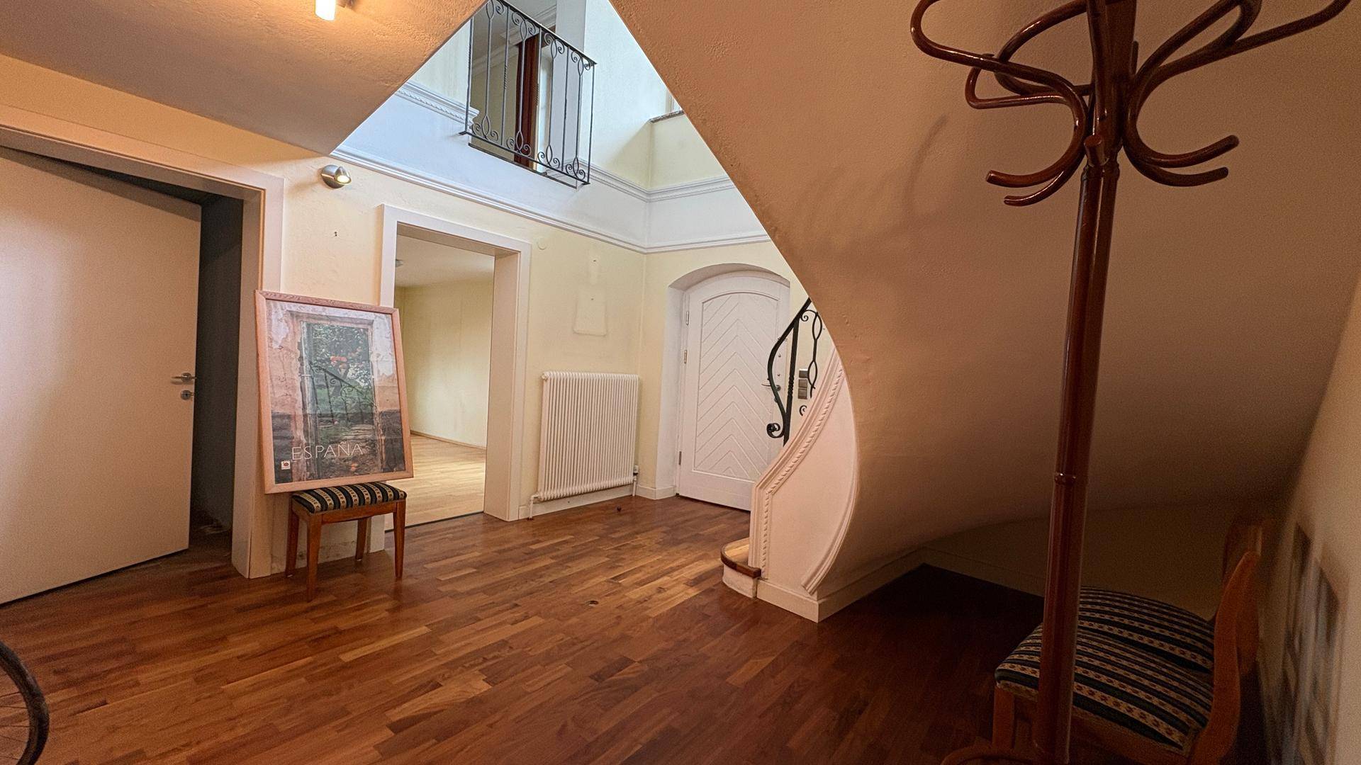 Geräumiger Eingangsbereich mit Holzparkett, geschwungener Treppe und Garderobe.