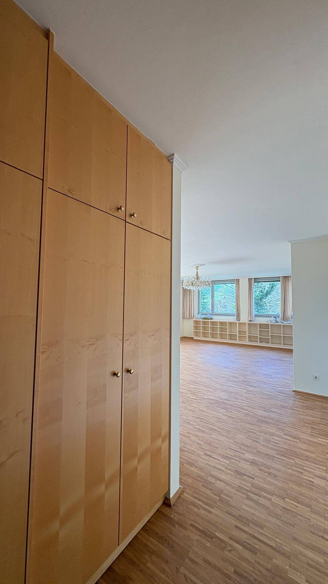 Flur mit praktischen, holzfarbenen Einbauschränken, die in den Wohnbereich führen.