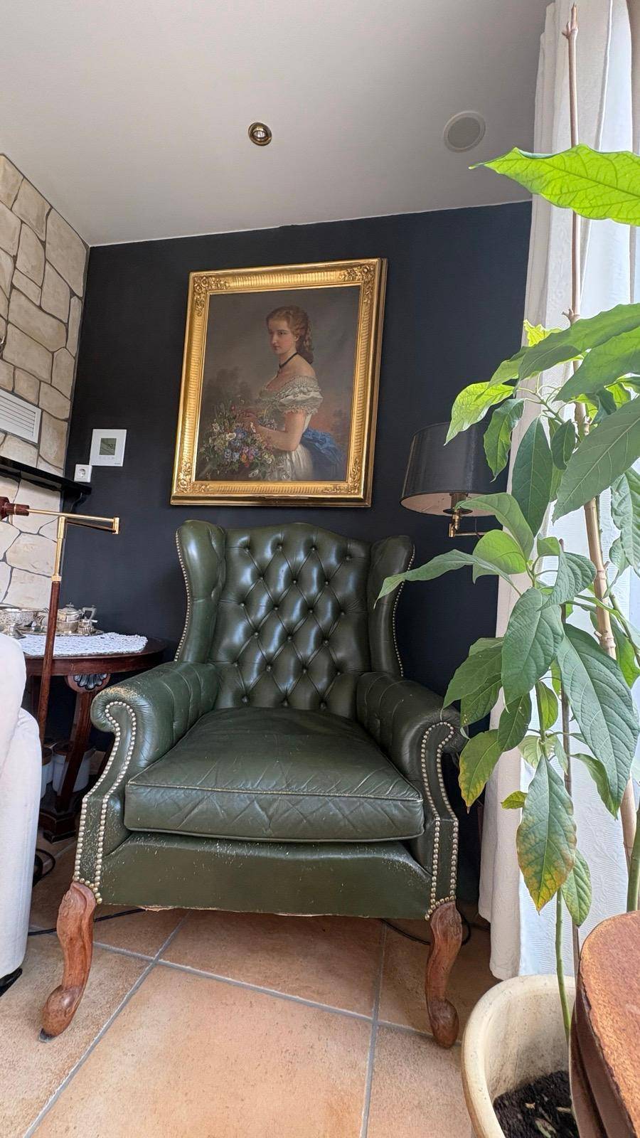 Elegante Sitzecke mit grünem Ledersessel, Kunstwerk und Zimmerpflanze.