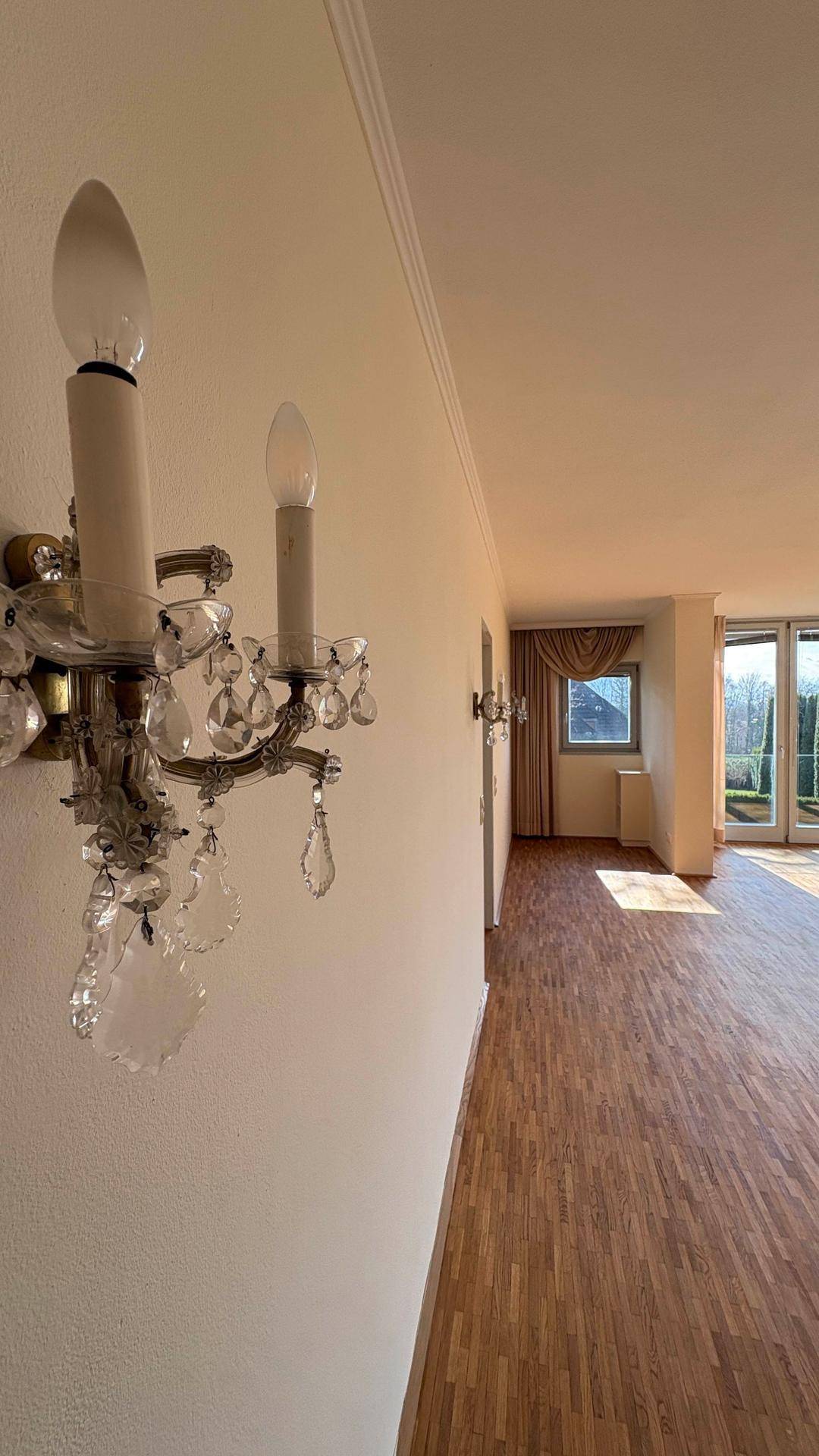 Eleganter Flur mit Wandleuchten und Parkettboden, der in den hellen Wohnbereich übergeht.