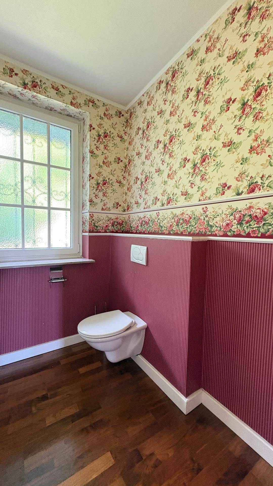 Gästetoilette mit floraler Tapete, Wand-WC und Fenster für natürliche Belüftung.