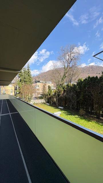 Langer Balkon mit Blick auf grüne Hügel und die umliegende Landschaft unter blauem Himmel.
