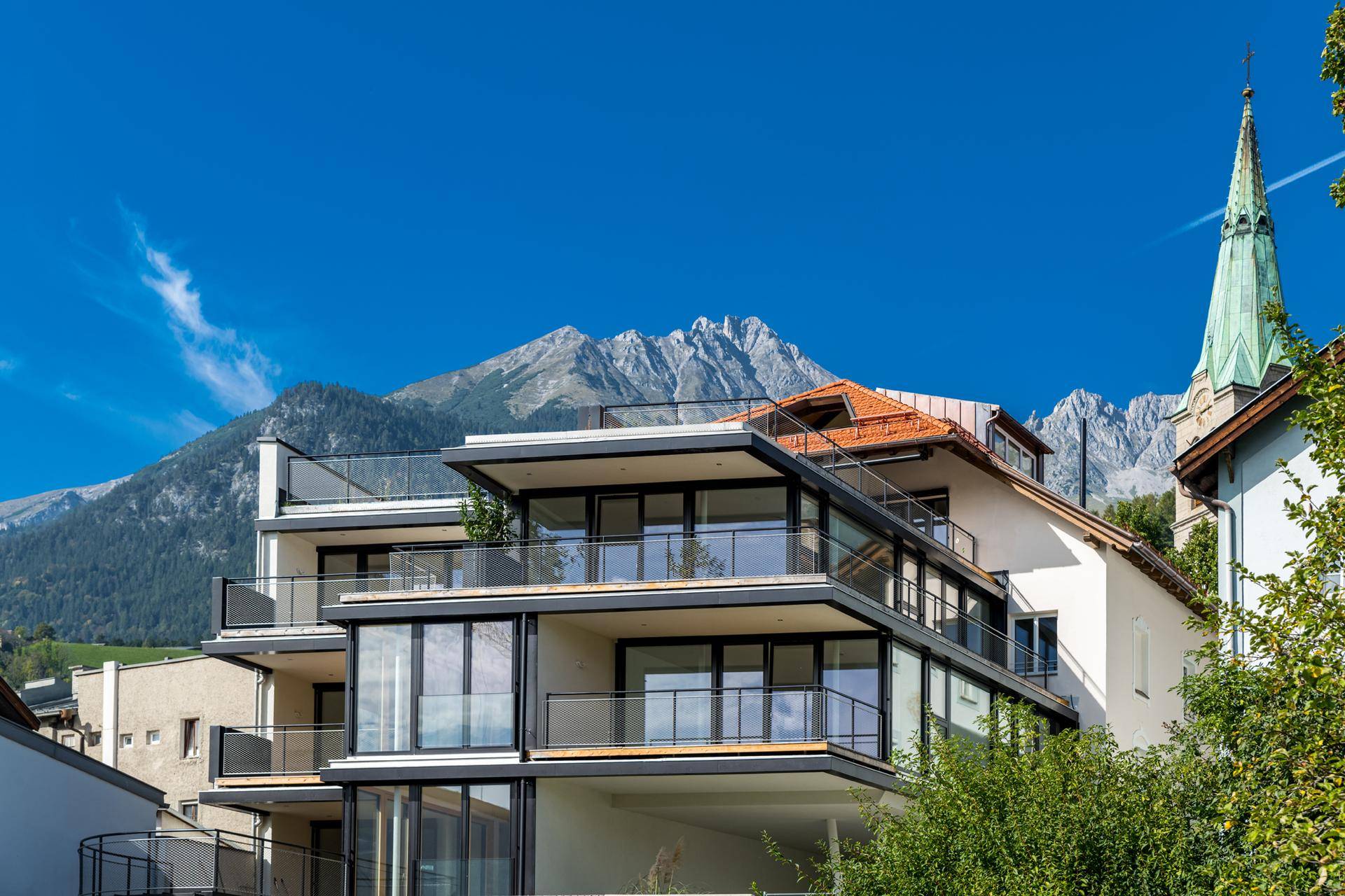 Attraktives Gebäude mit modernen Balkonen und beeindruckendem Bergblick im Hintergrund.