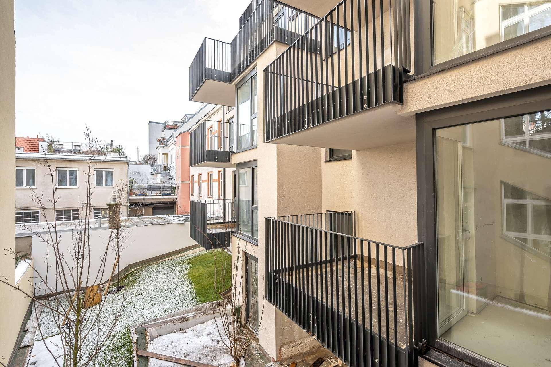 Blick auf die modernen Balkone mit schwarzen Geländern und den dahinterliegenden Innenhof.