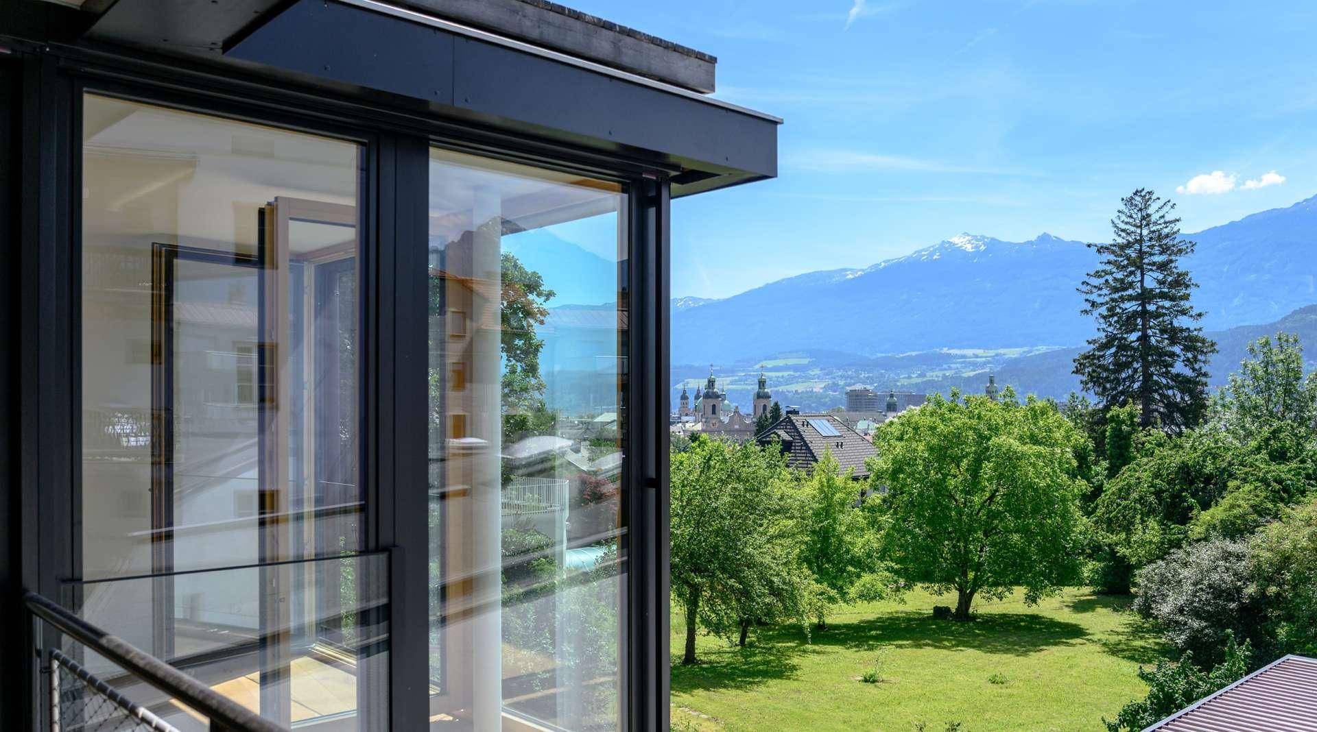 Panoramablick auf die majestätischen Berge und die grüne Umgebung von einem modernen Gebäude mit großen Glasflächen.
