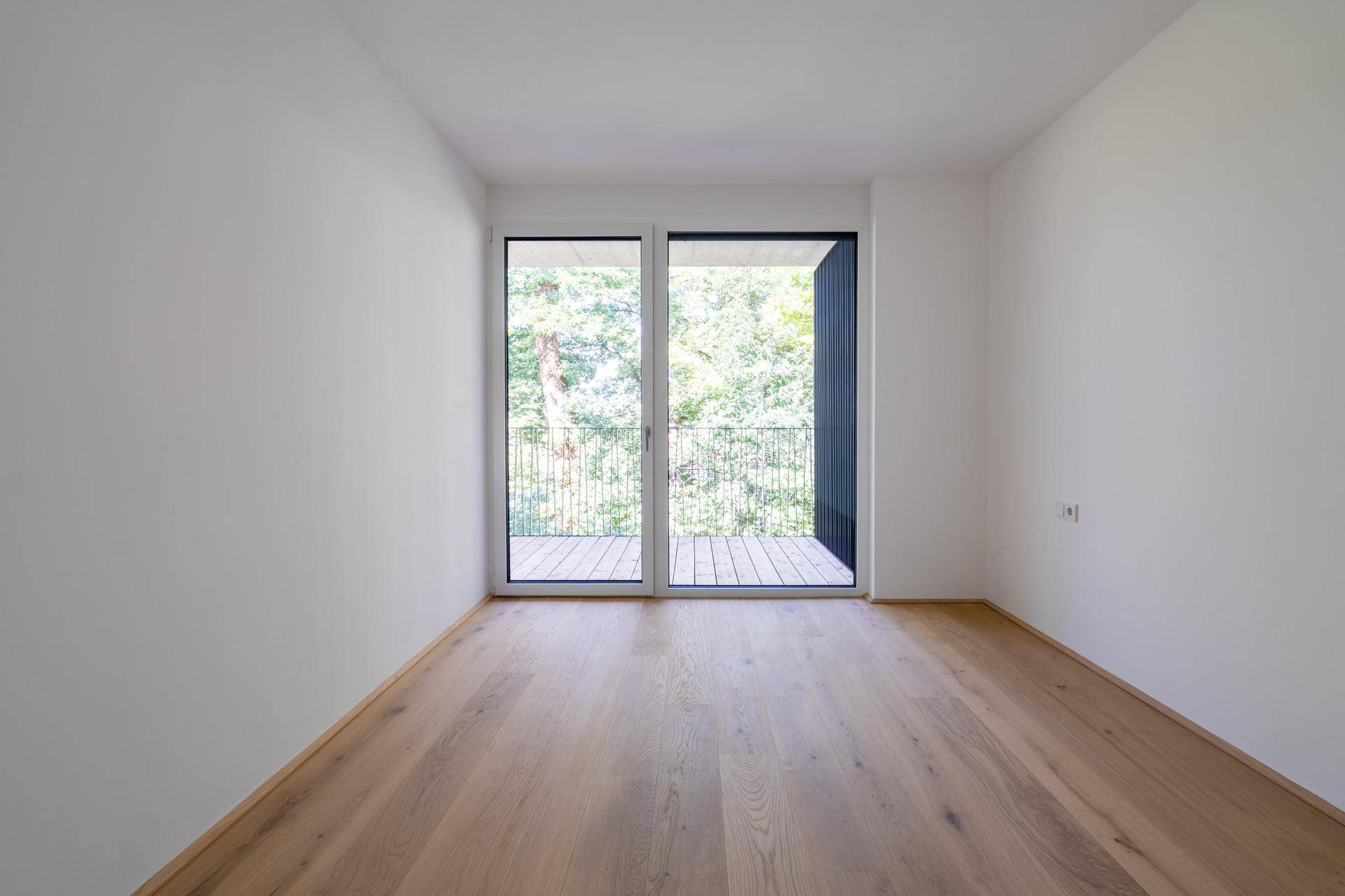 Lichtdurchfluteter Raum mit Holzboden und direktem Zugang zum Außenbereich.