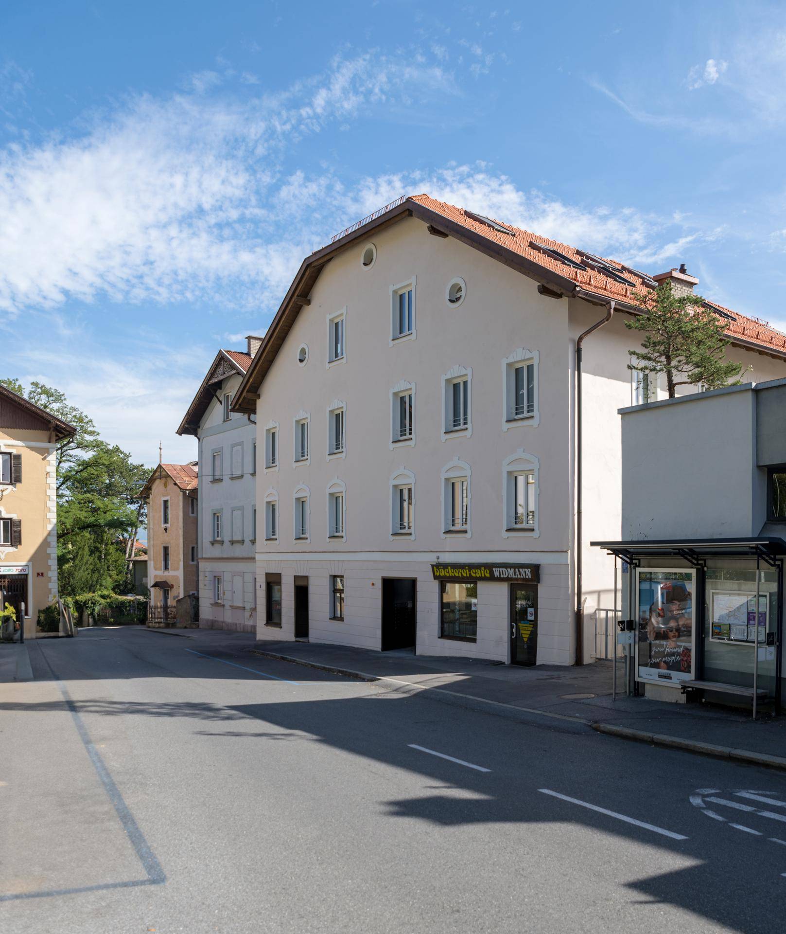 Historisches Gebäude an einer Straße mit Geschäften im Erdgeschoss und traditionellem Dach.