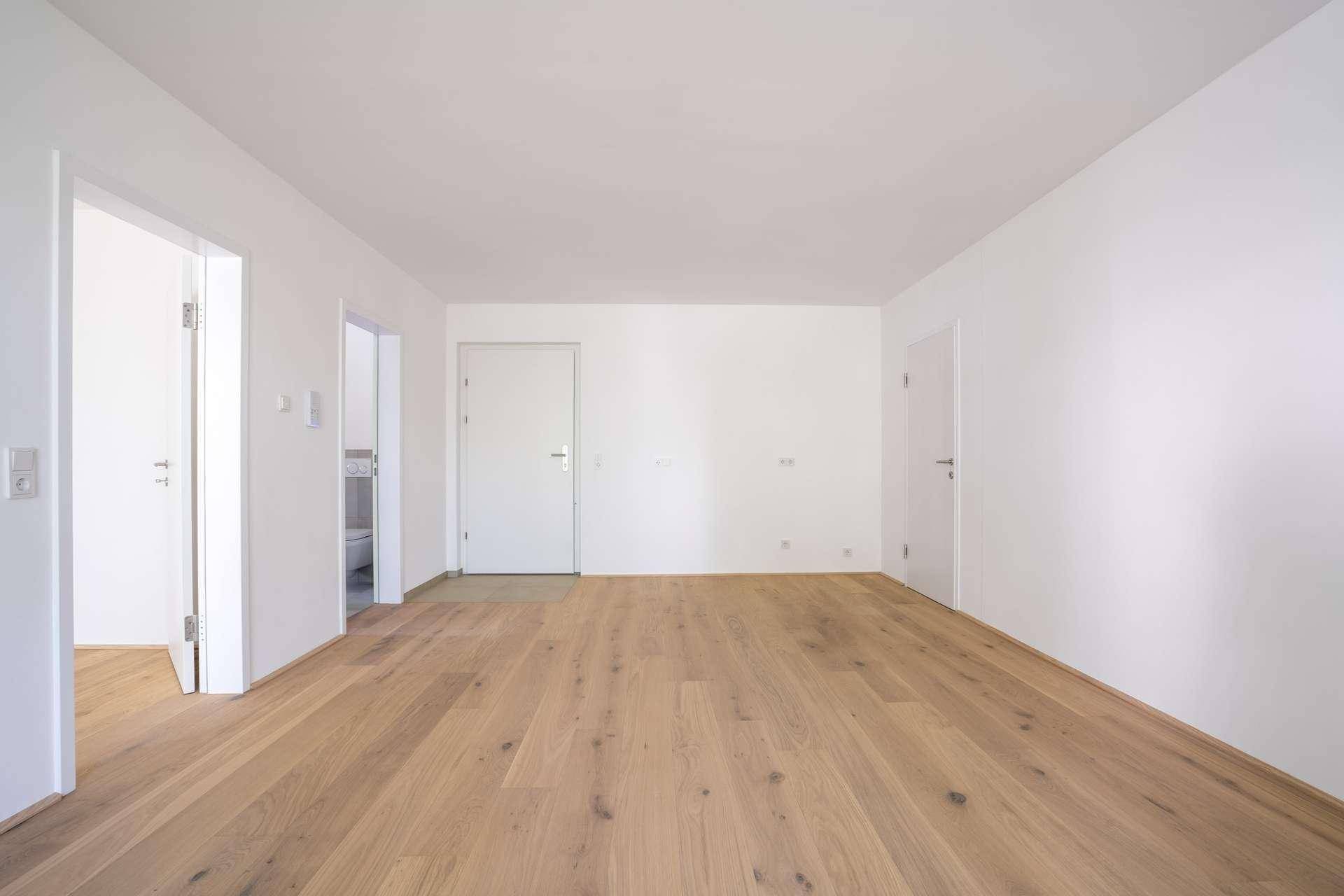 Geräumiger, heller Flur mit Holzboden und mehreren weißen Türen, der zu verschiedenen Räumen führt.