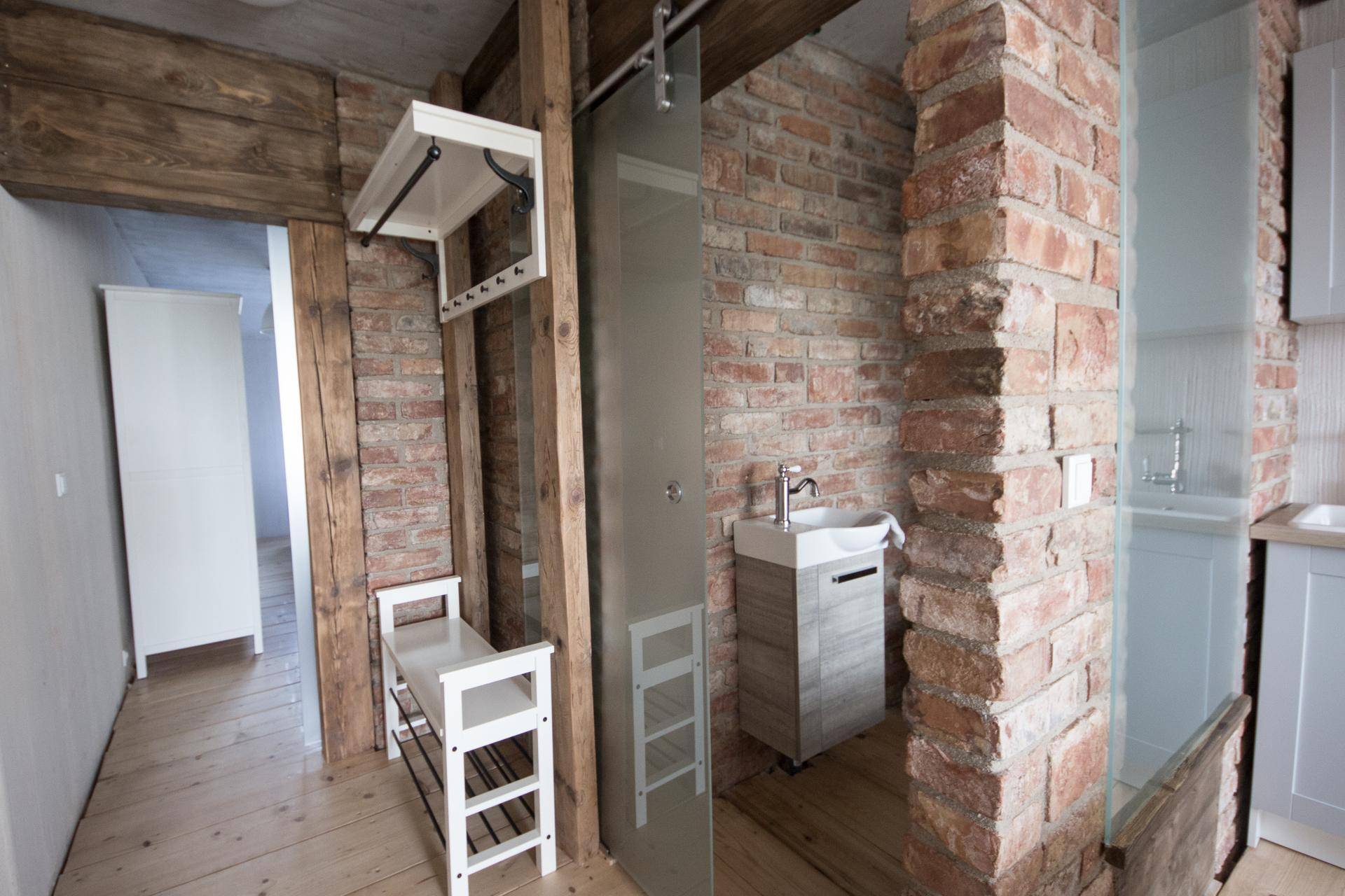 Eingangsbereich mit Holzboden, Ziegelwand und praktischer Garderobe mit Sitzbank.