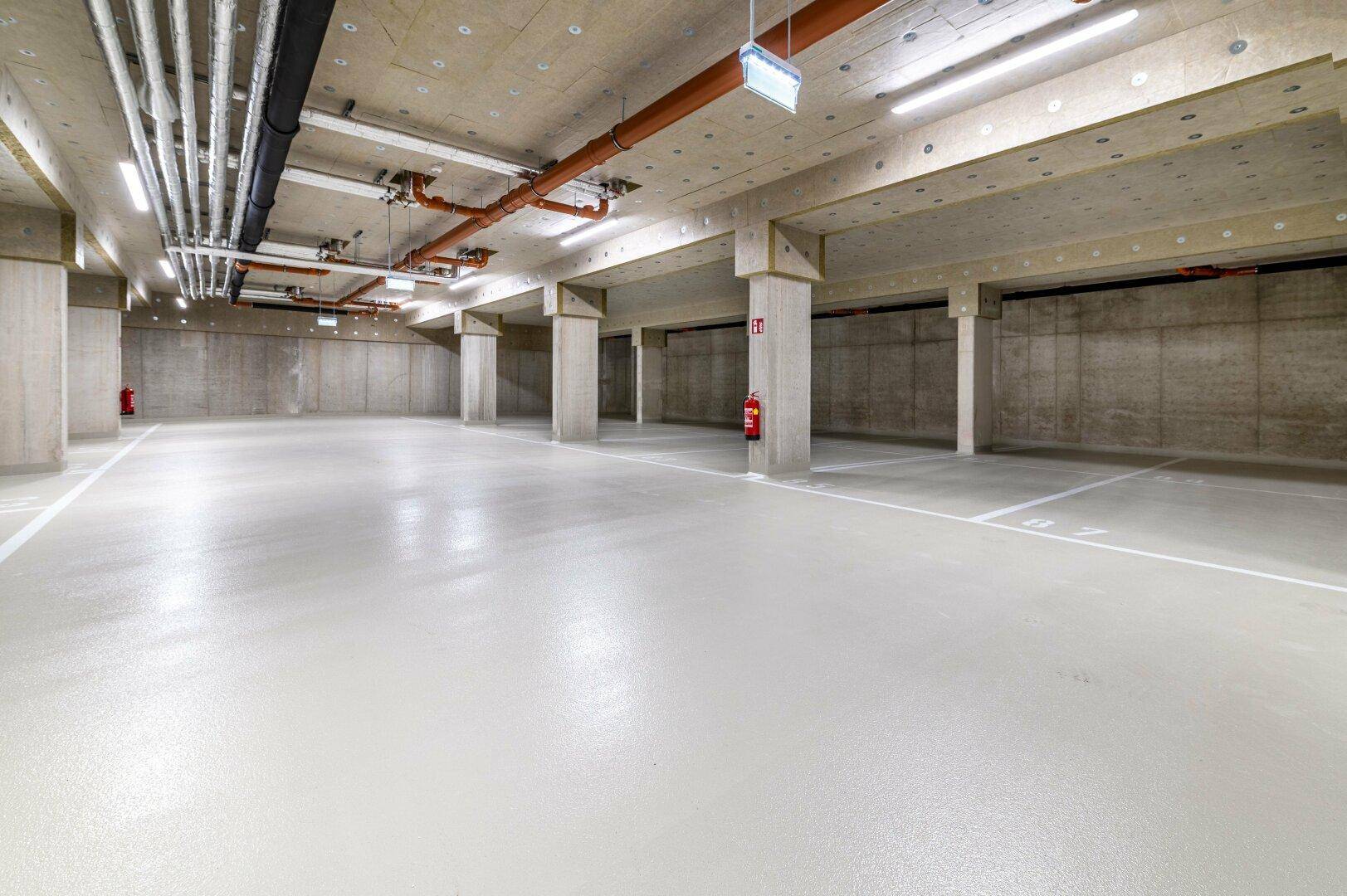 Geräumige Tiefgarage mit markierten Stellplätzen und moderner Beleuchtung.
