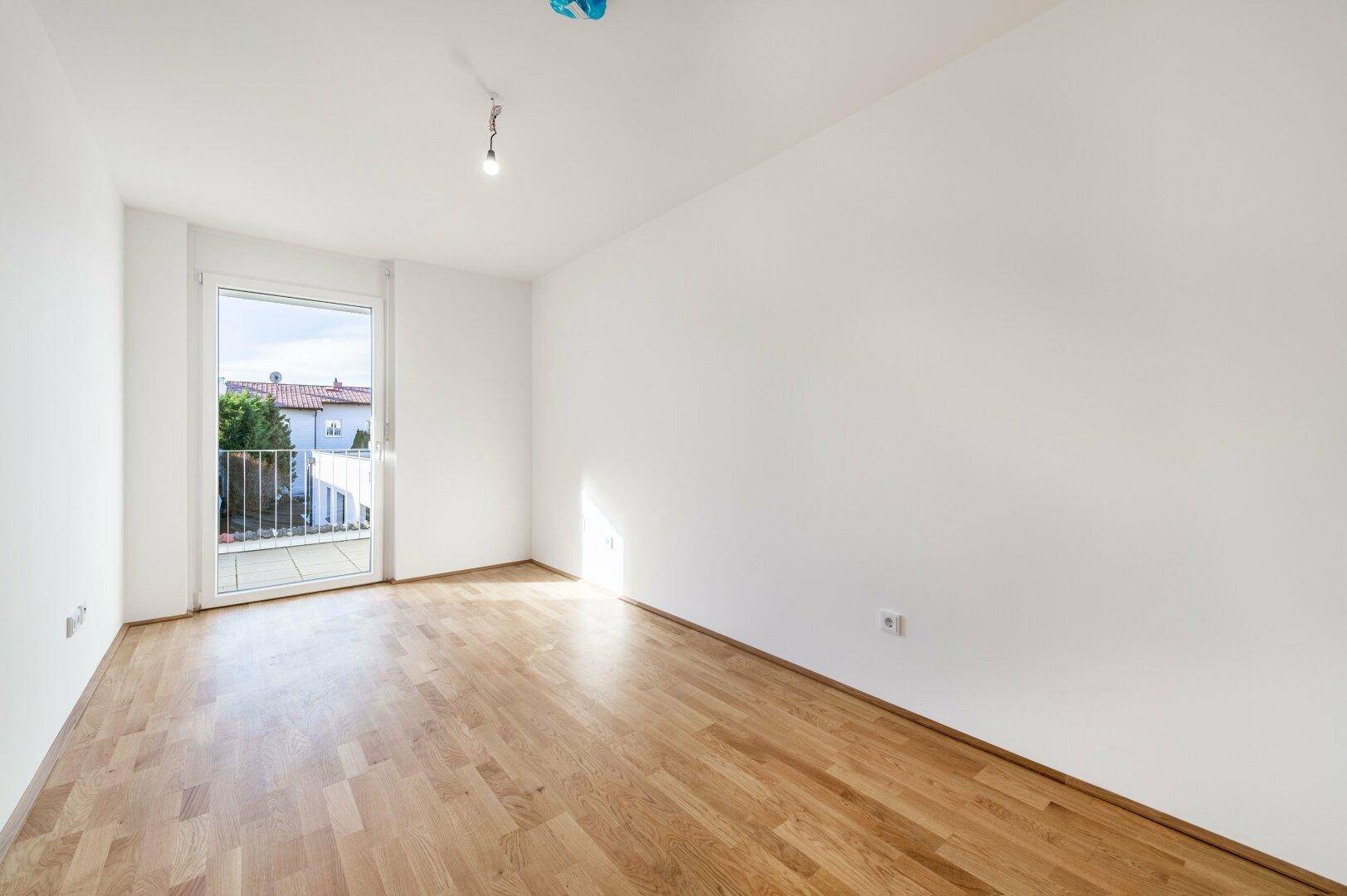 Geräumiges Schlafzimmer mit Holzboden und direktem Zugang zu einem kleinen Balkon.