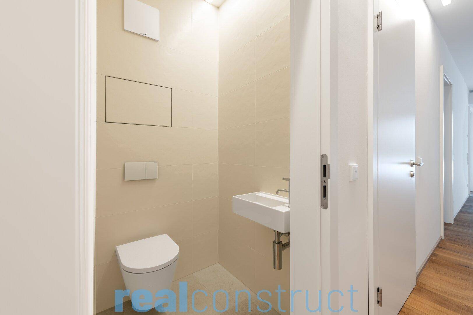 Modernes Gäste-WC mit wandhängender Toilette und kleinem Waschbecken.
