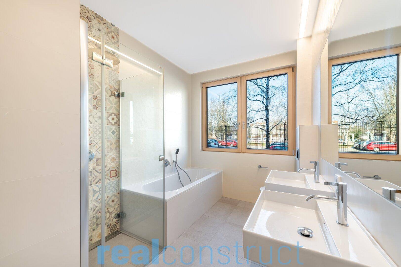 Modernes Badezimmer mit Doppelwaschbecken, Badewanne und Duschbereich.