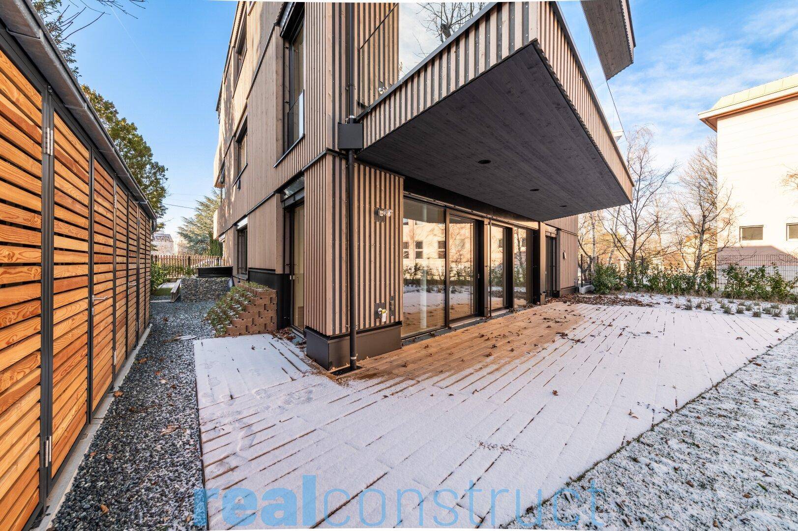Seitlicher Blick auf die moderne Holzfassade und die verschneite Terrasse.