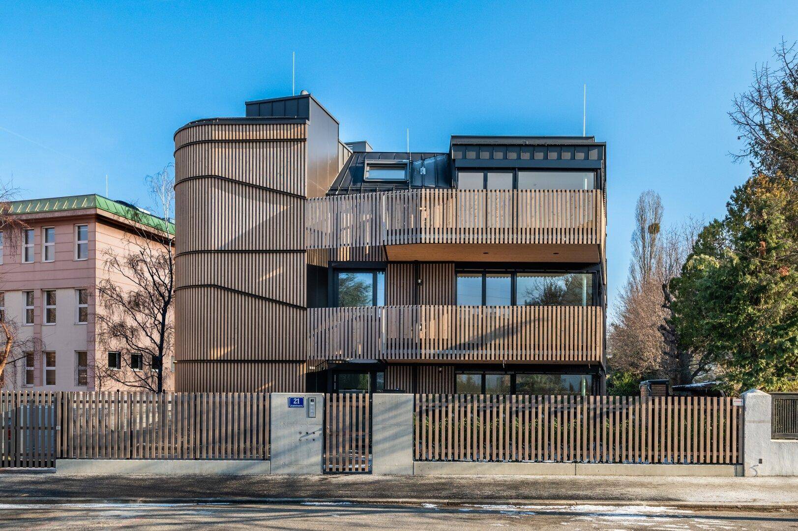 Moderne Wohnanlage mit Holzfassade, Balkonen und Glasgeländern.