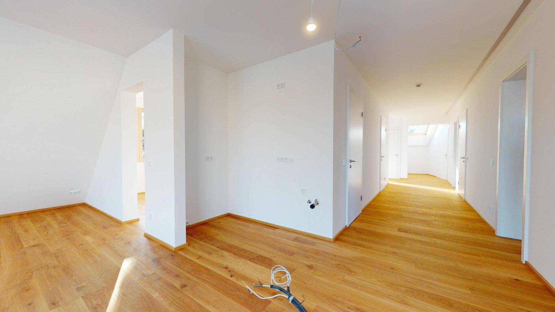 Heller Flur mit Holzboden und mehreren Türen, der zu verschiedenen Räumen der Wohnung führt.