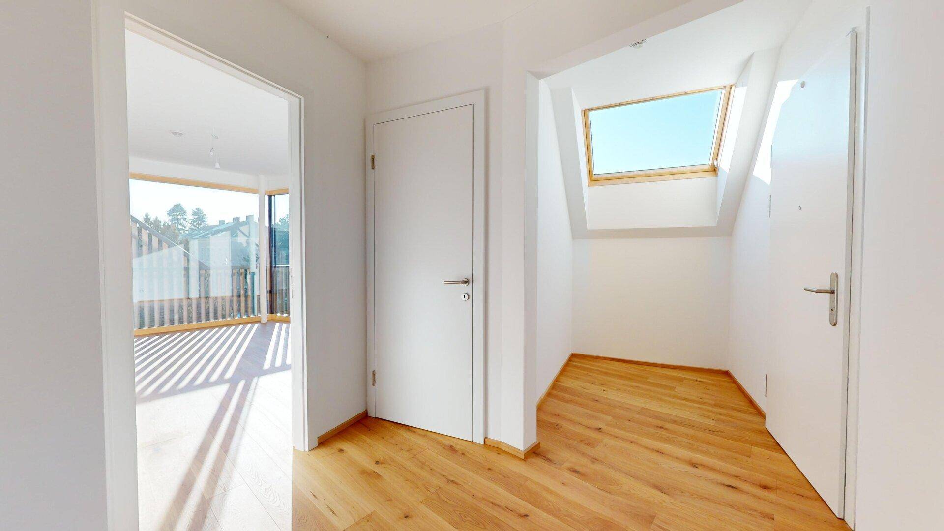 Heller Flur mit Holzboden und einem Dachfenster, das zusätzliches Tageslicht in den Bereich spendet.