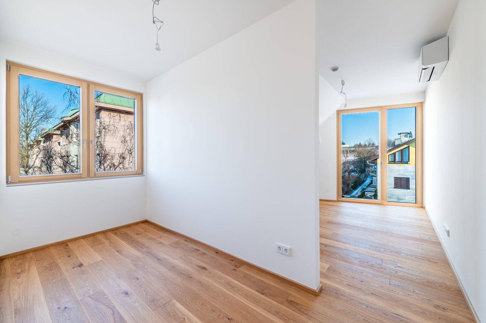 Zwei helle Räume mit Holzboden und Fenstern, einer davon mit Klimaanlage ausgestattet, ideal als Schlafzimmer.