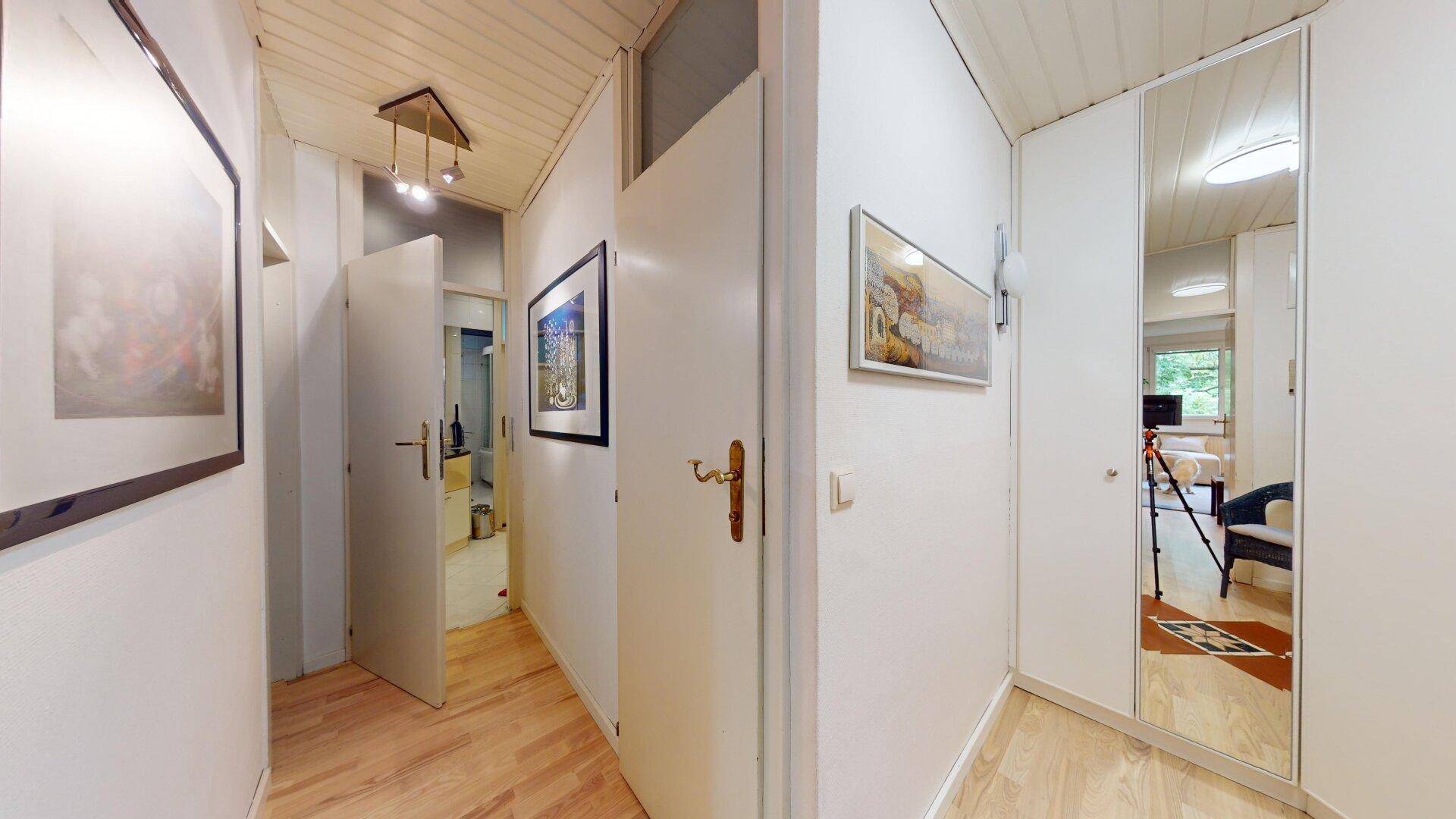 Heller Flur mit Holzboden, Spiegelschrank und Zugang zu verschiedenen Zimmern, gut organisiert.