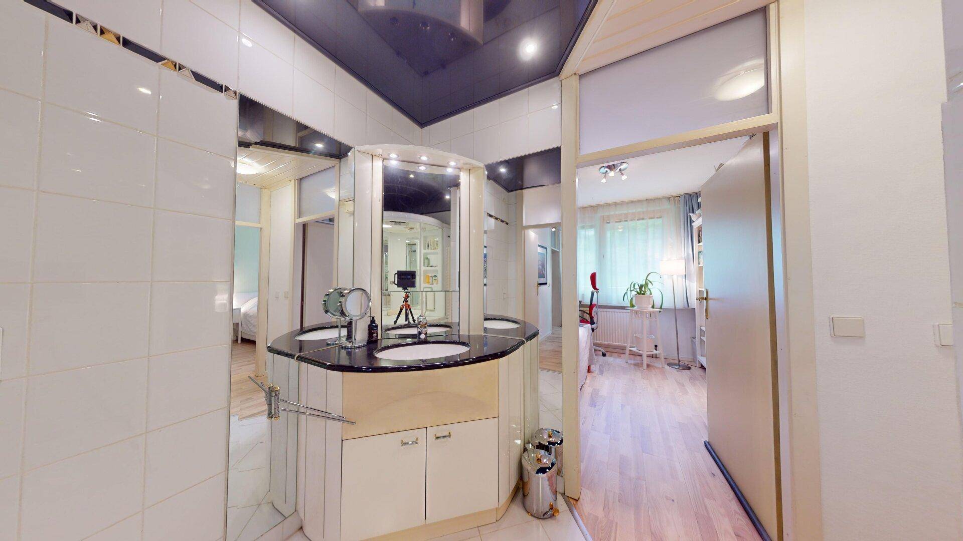 Badezimmer mit Doppelwaschbecken, Spiegelschrank und hellem Fliesenboden, geräumig und modern.