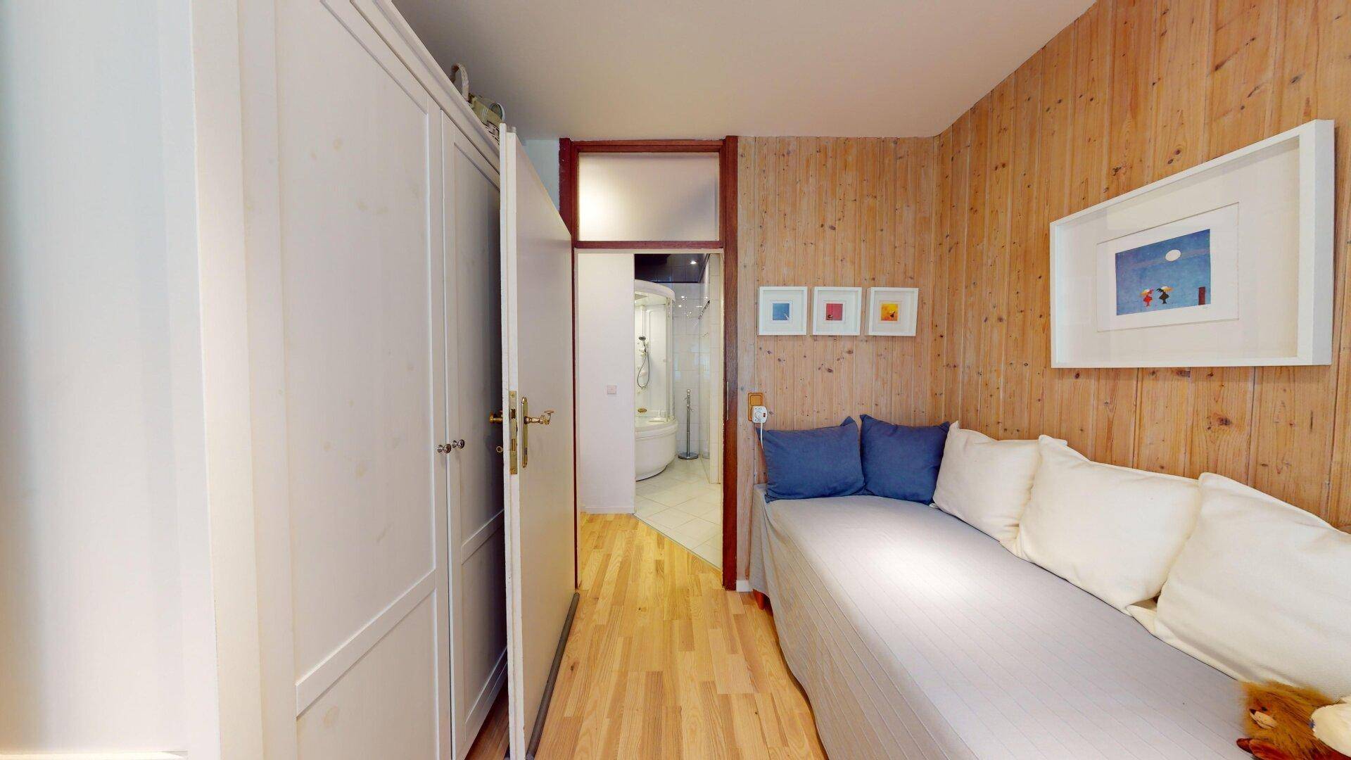 Schlafzimmer mit Holzwänden, Einbauschrank und Zugang zum Badezimmer, praktisch und einladend.