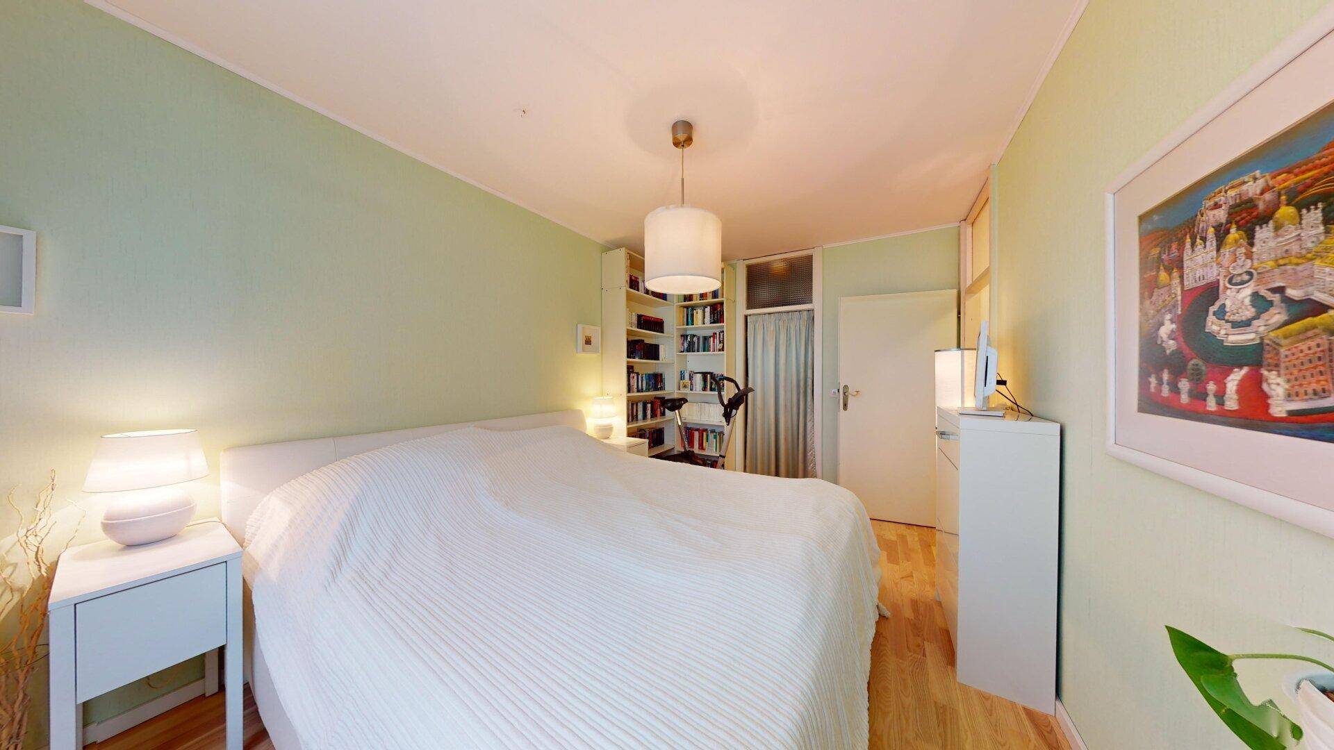 Schlafzimmer mit Doppelbett, Nachttischen und Kunstwerken an der Wand, hell und persönlich gestaltet.