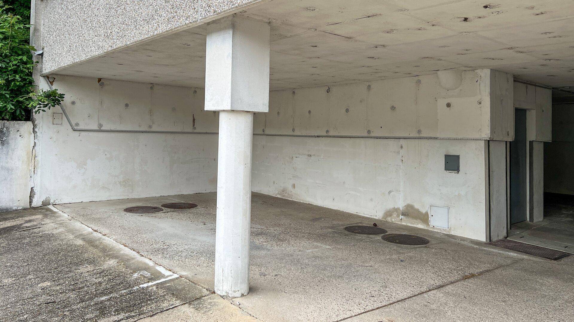 Überdachter Bereich mit Betonpfeiler, der als Parkplatz oder Eingangsbereich dient.