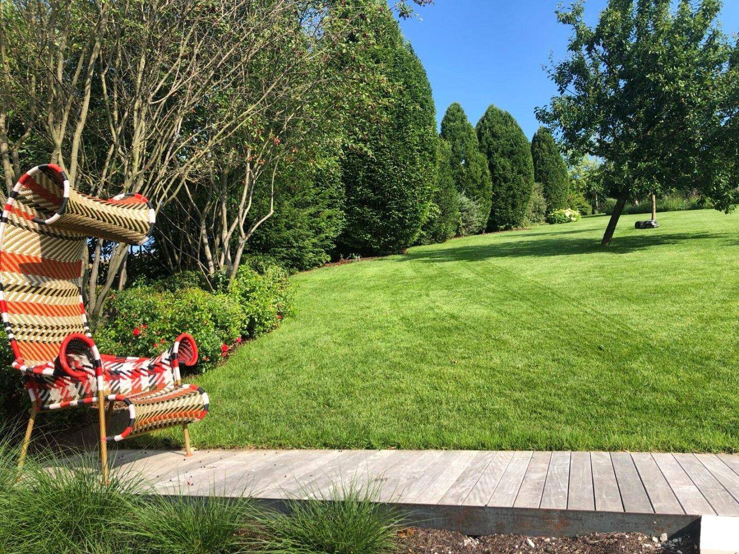 Idyllischer Gartenbereich mit üppigem Grün, hohen Bäumen und einer einzigartigen Sitzgelegenheit.