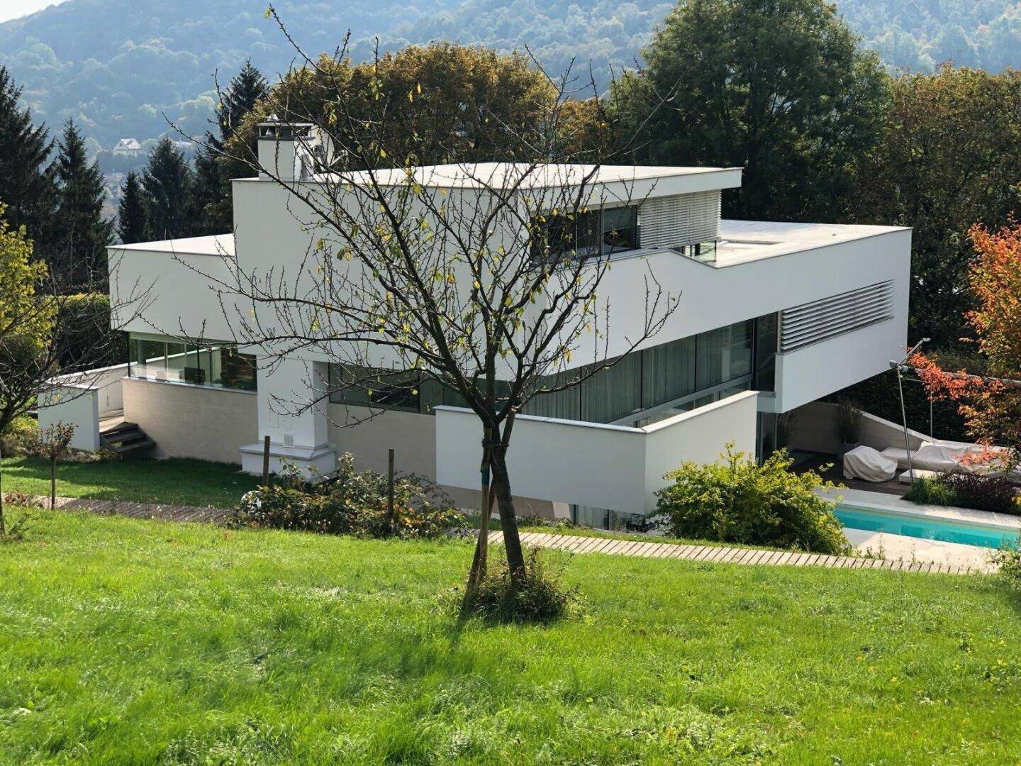 Elegante, weiße Villa in einer grünen Hügellandschaft mit weitem Blick auf die Umgebung.