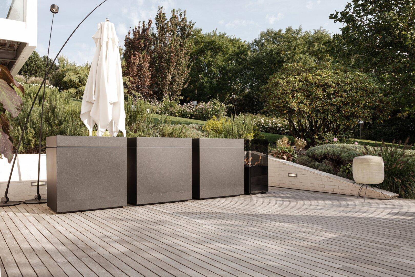 Geräumige Holzterrasse mit eleganter Outdoor-Küche und Schirm, ideal für entspannte Stunden im Freien.
