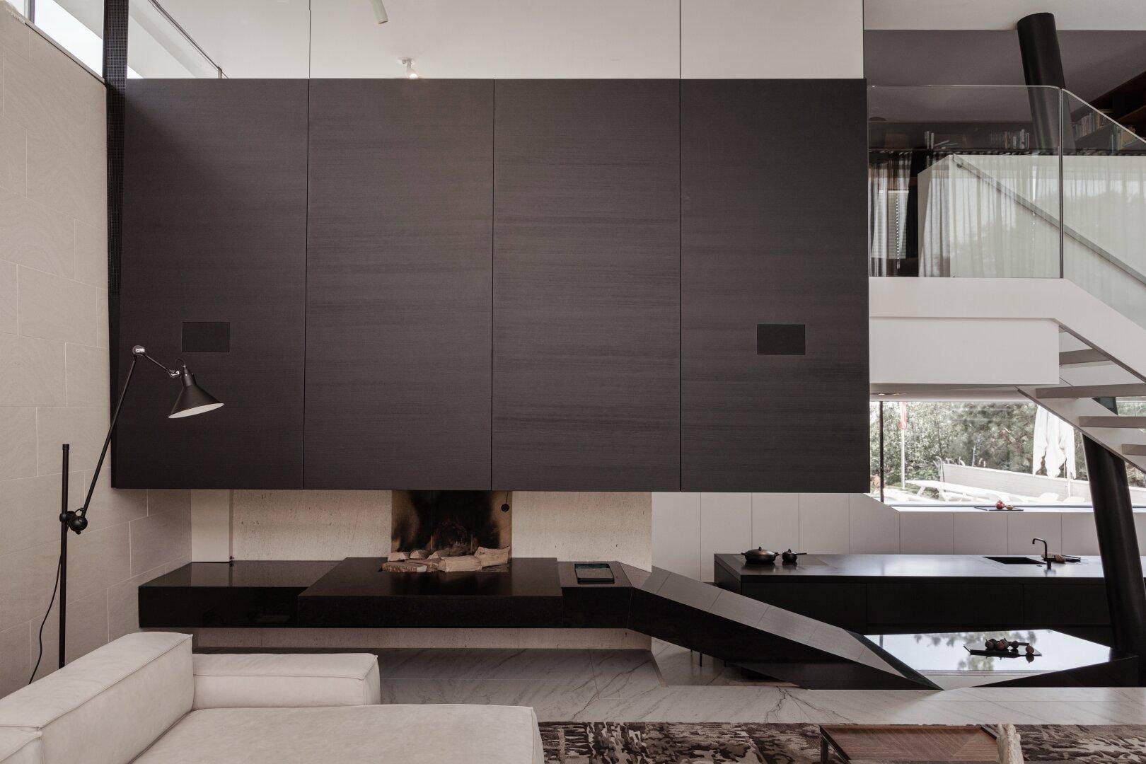 Elegantes Wohnzimmer mit integriertem Kamin, dunklen Einbauschränken und Marmorboden.