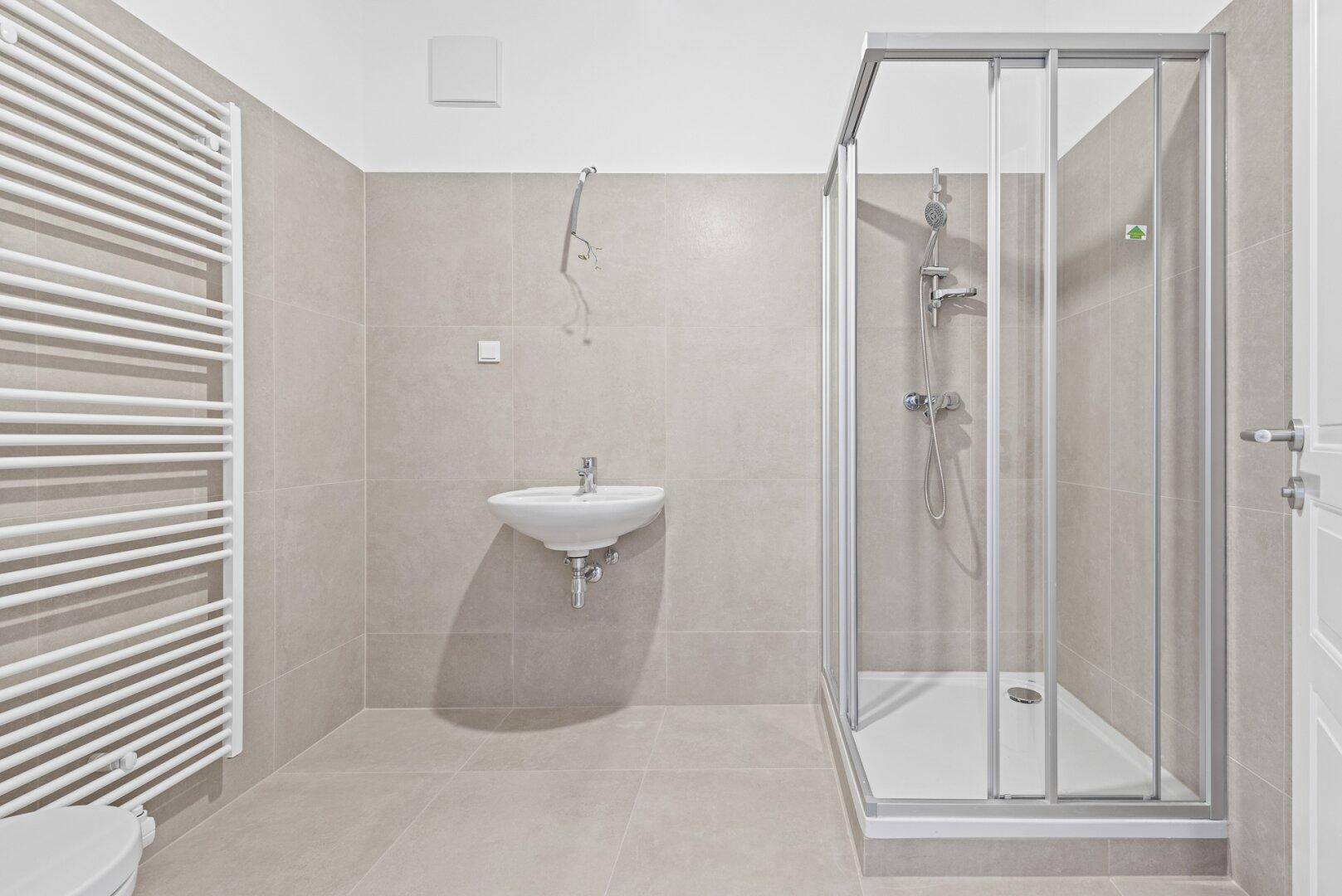 Modernes Badezimmer mit Duschkabine, Waschbecken und beheiztem Handtuchhalter.