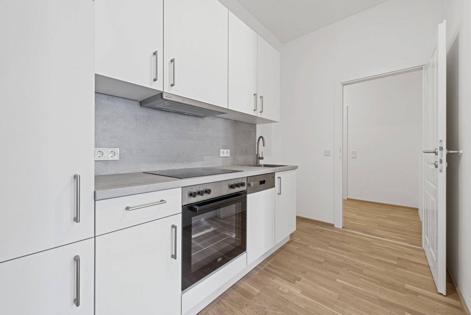 Funktionale Küchenzeile mit weißen Schränken, Backofen und Kochfeld, ideal für kleine Wohnungen.