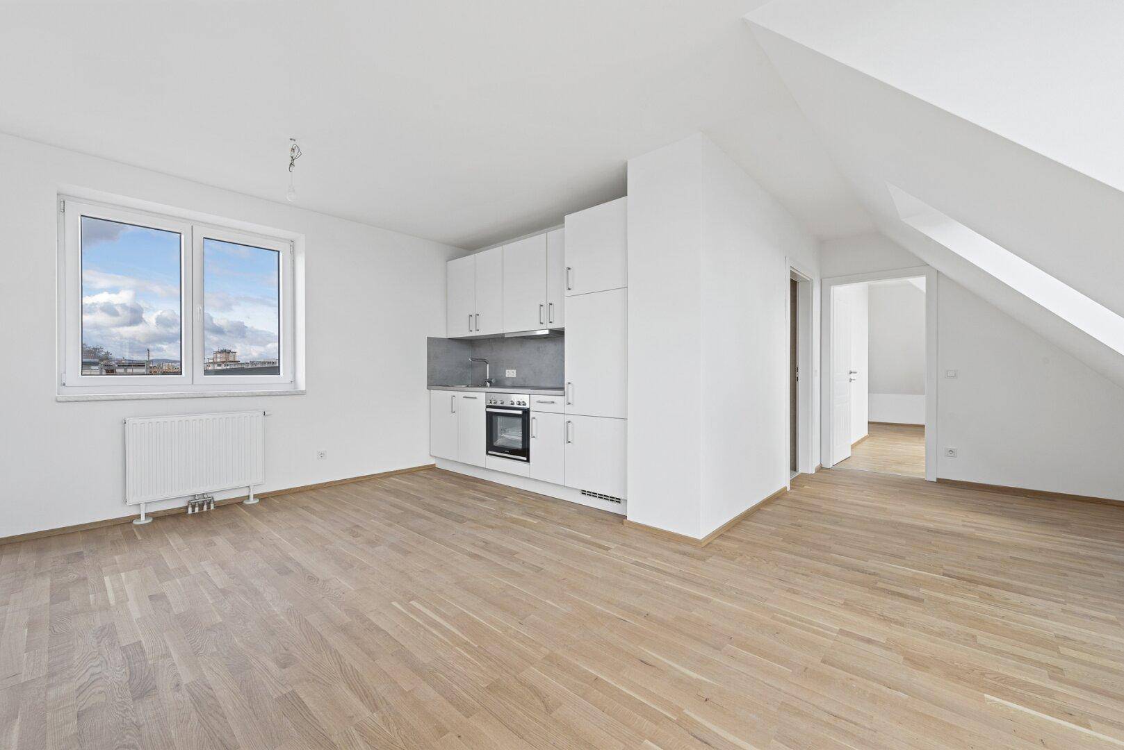 Moderne Küchenzeile in offenem Raum mit Holzboden und großem Fenster.