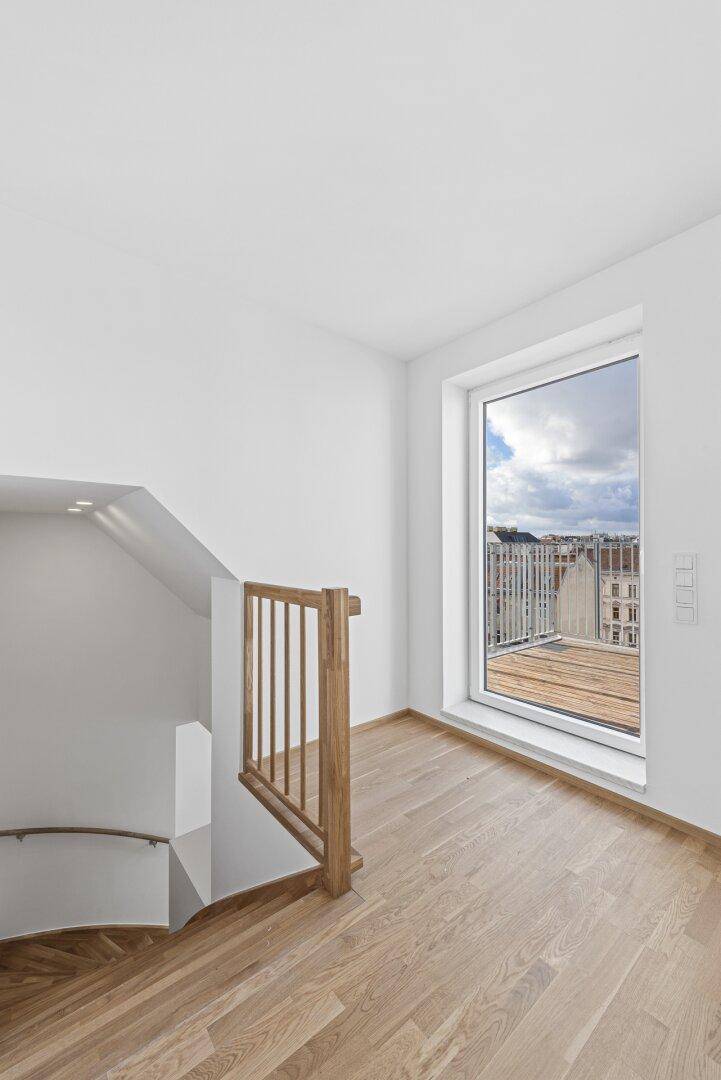Heller Flurbereich mit Holzboden und Zugang zu einem Balkon mit Stadtblick.