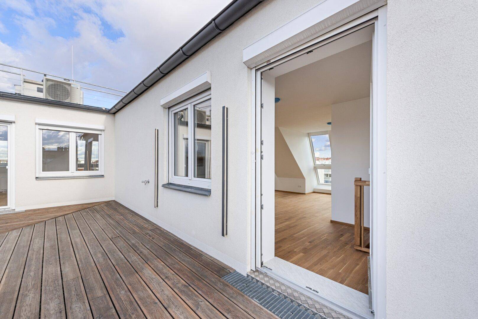 Zugang zur Dachterrasse mit Holzboden und Blick in den hellen Innenraum.